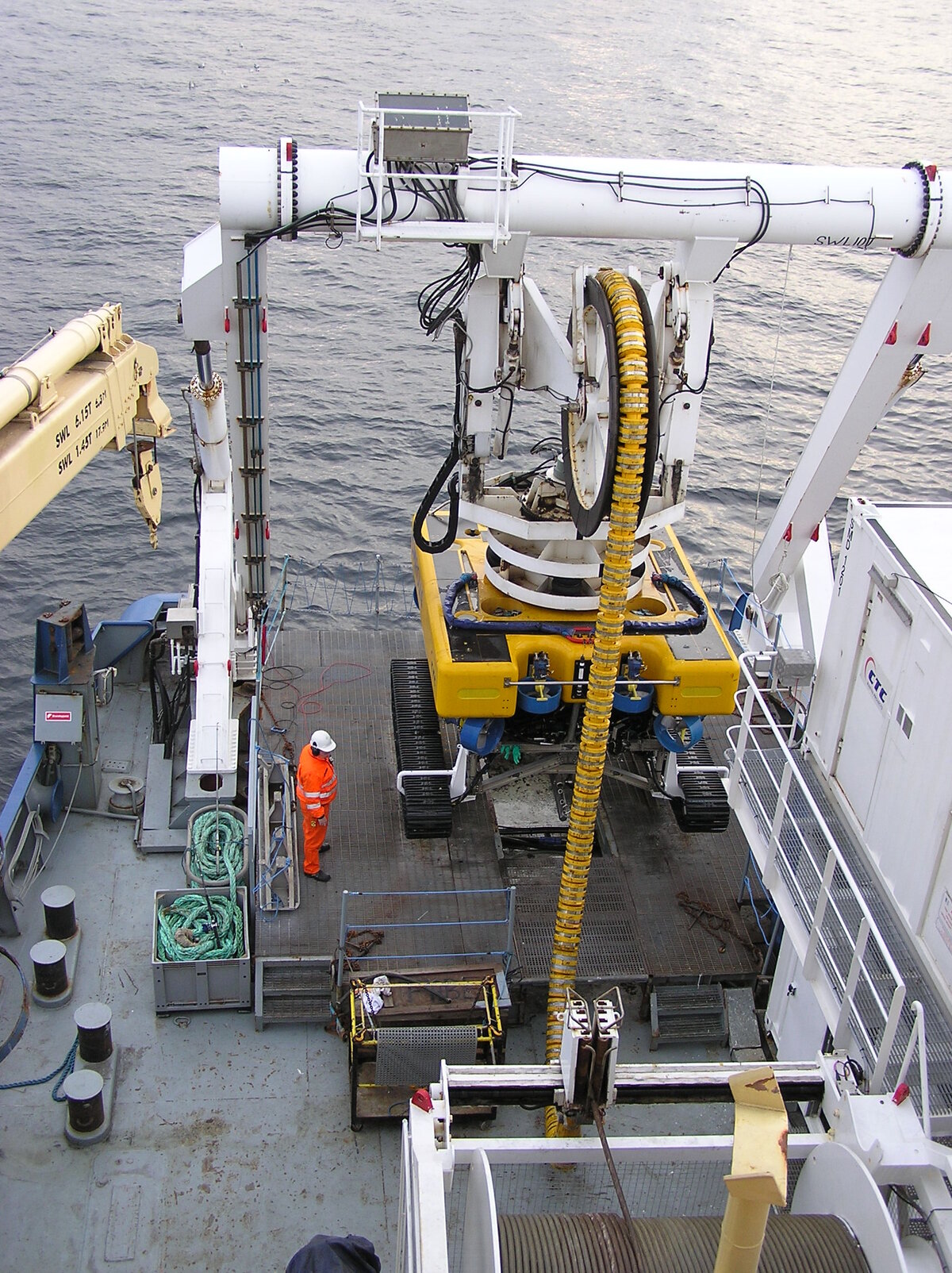Crew on a cable ship launching a tethered remotely operated vehicle over the side