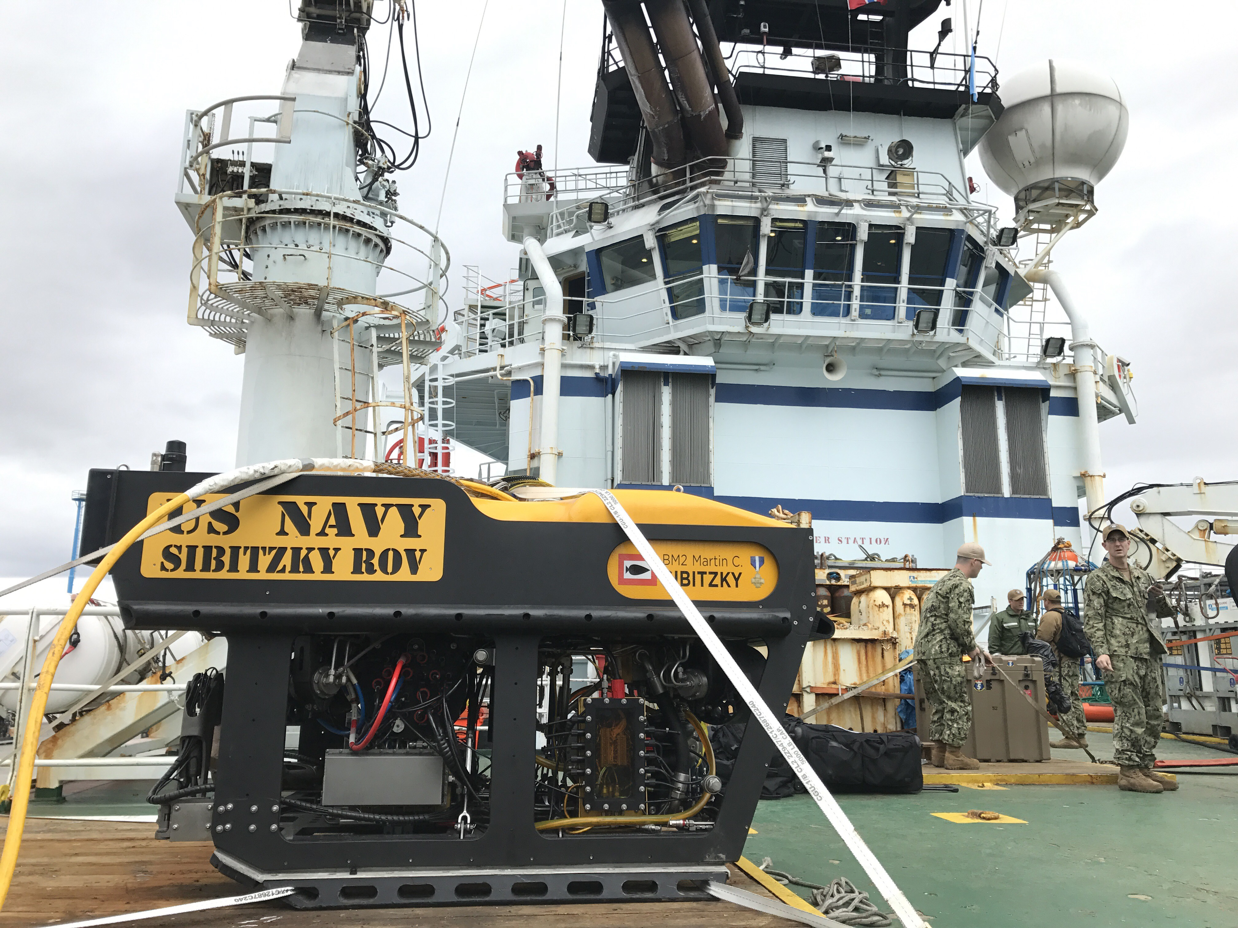 Yellow remotely operated underwater vehicle on a ship deck, not a BlueROV2