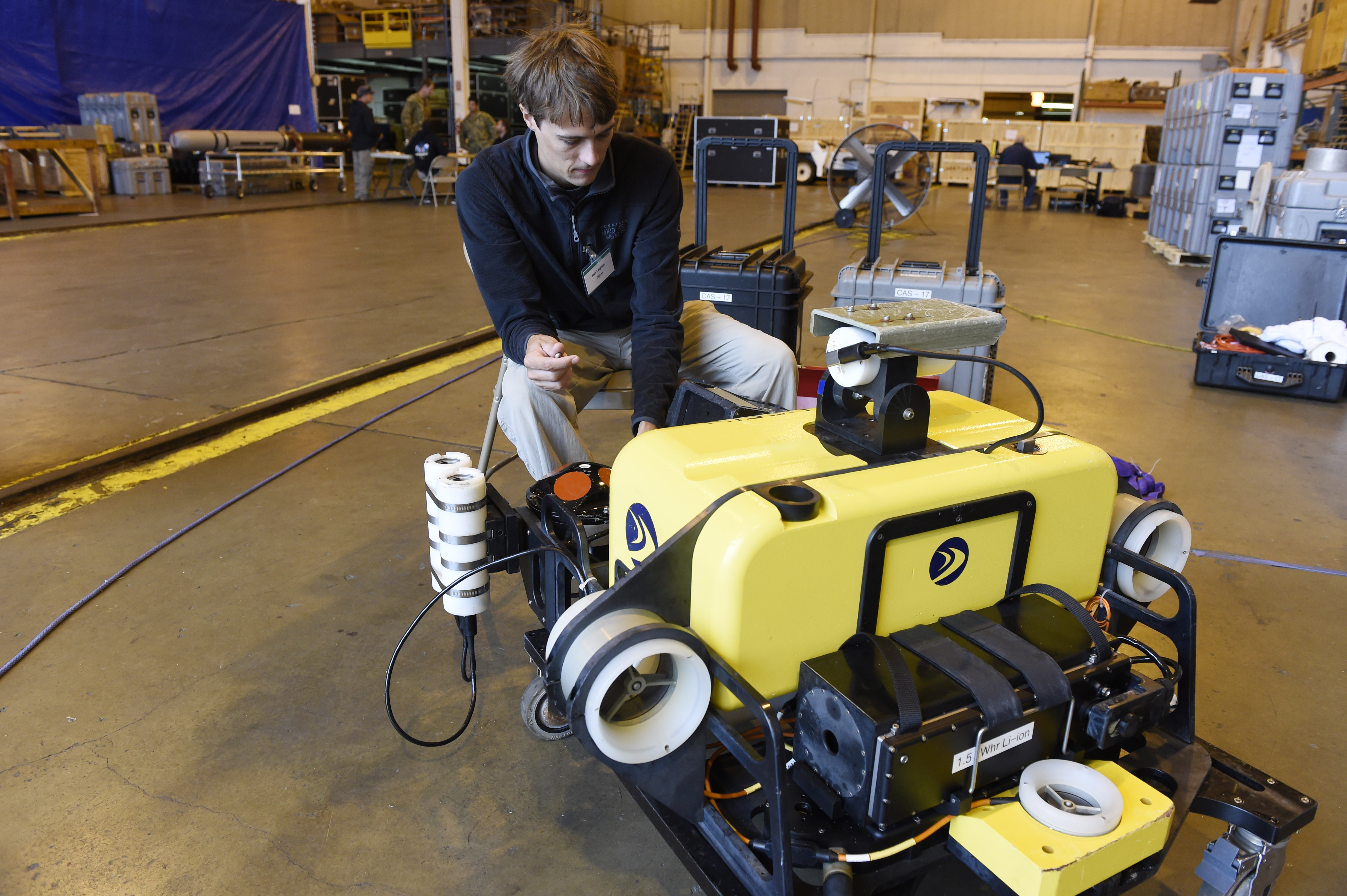 Person adjusting a remotely operated underwater vehicle on a pier